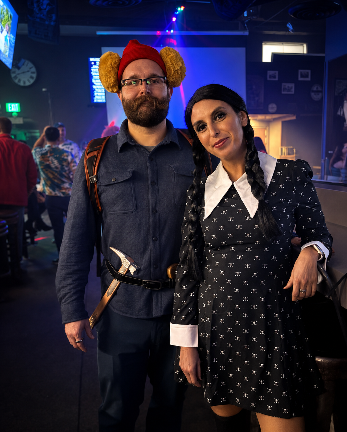 A couple in costume inside the bar under blue and purple party lights on Halloween night.